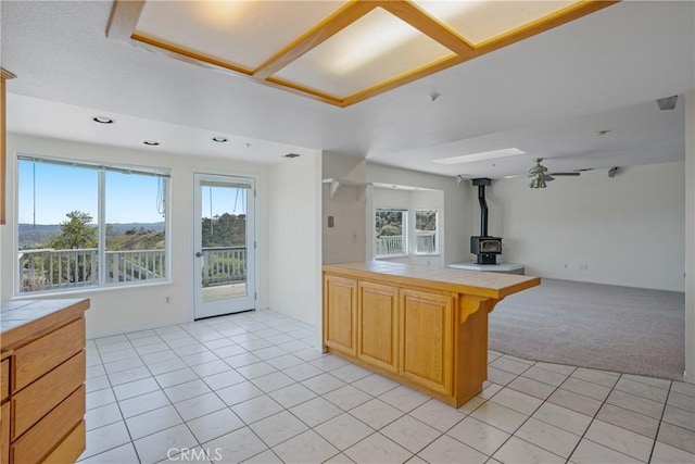 kitchen featuring open floor plan, light tile patterned flooring, tile countertops, and a wood stove