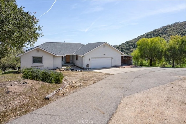 ranch-style home featuring driveway, a shingled roof, and a garage