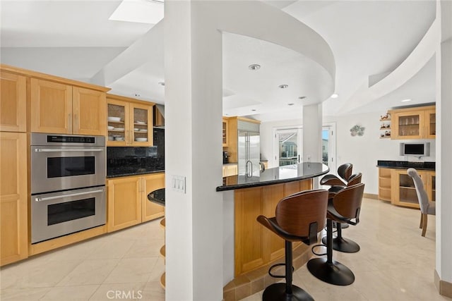 16449 Ladona Cir, Huntington Beach, CA 92649 - kitchen featuring appliances with stainless steel finishes, a kitchen bar, glass insert cabinets, tasteful backsplash, and recessed lighting