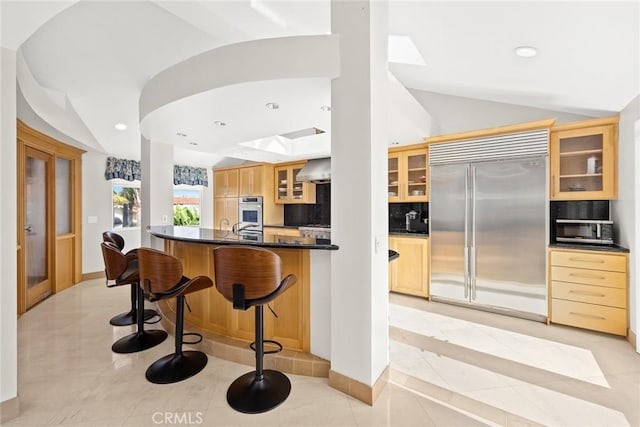 16449 Ladona Cir, Huntington Beach, CA 92649 - kitchen featuring appliances with stainless steel finishes, dark countertops, glass insert cabinets, light tile patterned floors, and a skylight