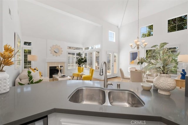 kitchen with high vaulted ceiling, an inviting chandelier, a fireplace, a sink, and open floor plan