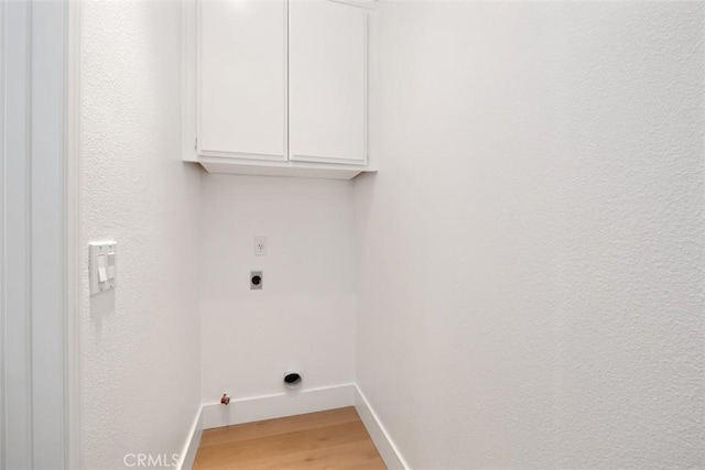 washroom featuring light wood finished floors, cabinet space, baseboards, and hookup for an electric dryer