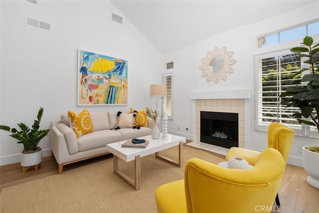 living room featuring a wealth of natural light, visible vents, wood finished floors, and a tile fireplace