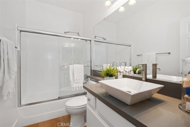 bathroom featuring vanity, toilet, wood finished floors, and combined bath / shower with glass door