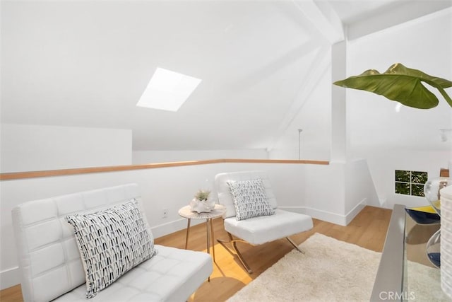 sitting room featuring baseboards, lofted ceiling with skylight, and wood finished floors