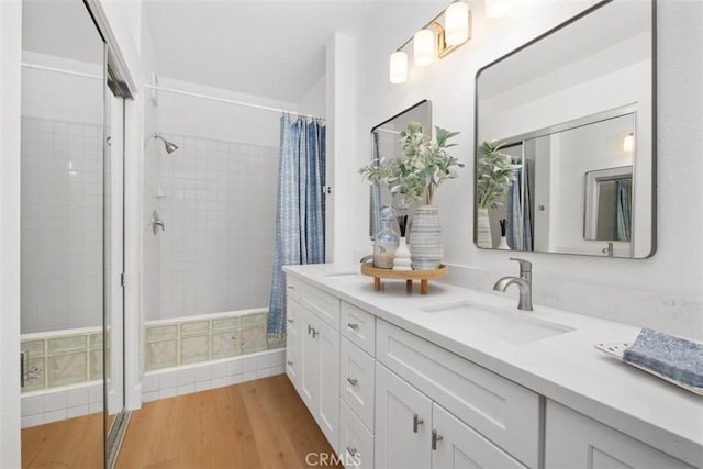 full bathroom featuring tiled shower, wood finished floors, and vanity