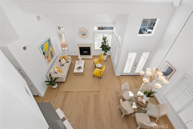 living area with a tiled fireplace, a towering ceiling, and wood finished floors