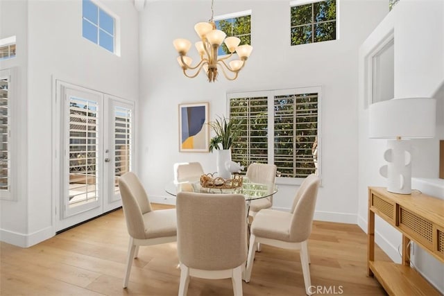 dining area featuring a high ceiling, light wood-style floors, baseboards, and a chandelier