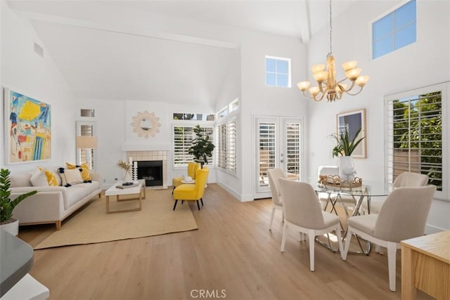 dining space with a chandelier, high vaulted ceiling, light wood finished floors, and a fireplace