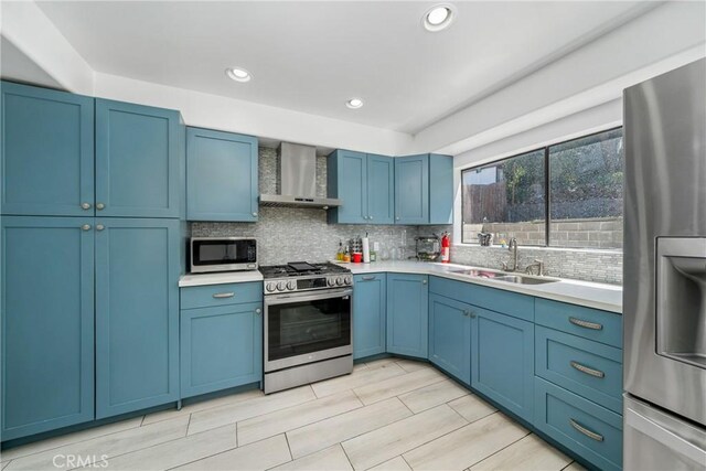 1116 Herbert Ave, Los Angeles, CA 90063 - kitchen featuring appliances with stainless steel finishes, wall chimney exhaust hood, a sink, blue cabinetry, and tasteful backsplash