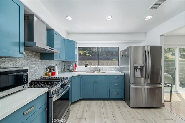 1116 Herbert Ave, Los Angeles, CA 90063 - kitchen with appliances with stainless steel finishes, wall chimney range hood, a sink, blue cabinets, and backsplash