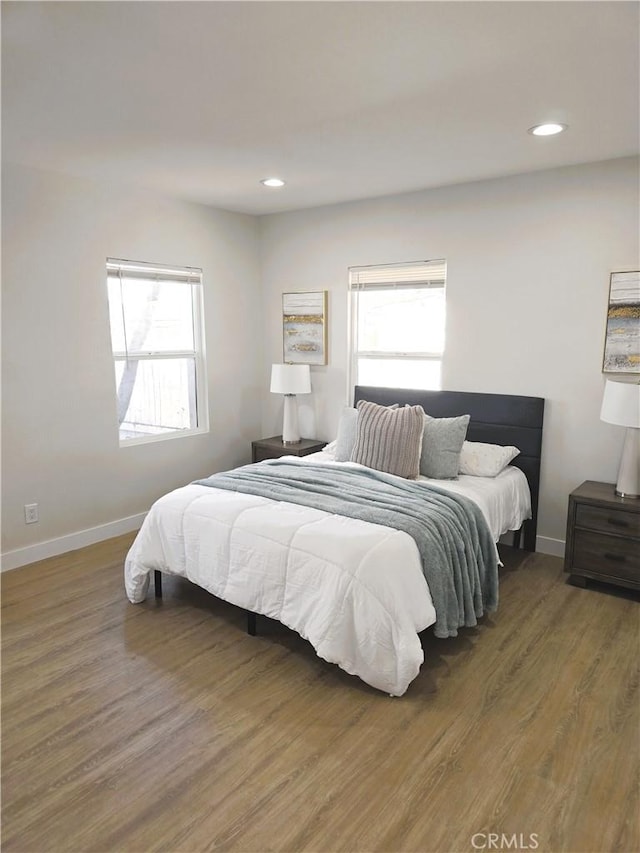 bedroom featuring baseboards, multiple windows, and wood finished floors