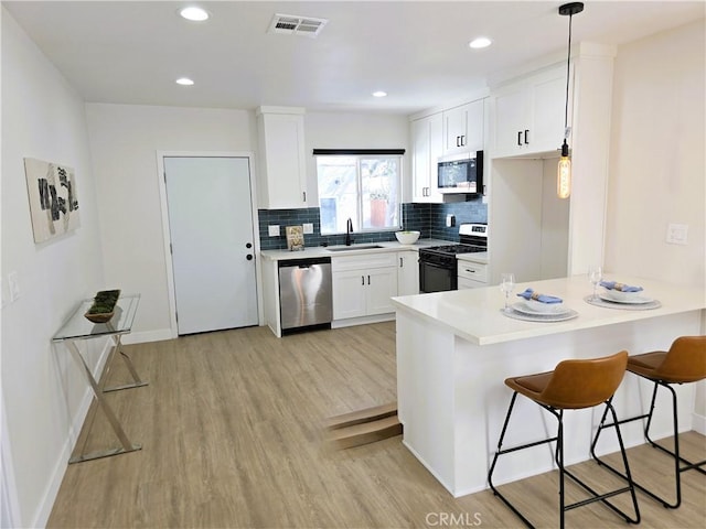 kitchen featuring a sink, tasteful backsplash, stainless steel appliances, a peninsula, and a breakfast bar area