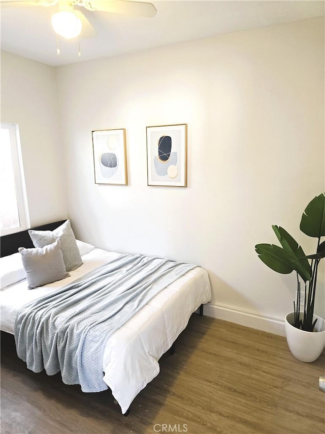 bedroom featuring ceiling fan, baseboards, and wood finished floors