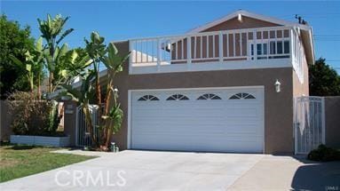 view of front of house featuring stucco siding, a balcony, and driveway