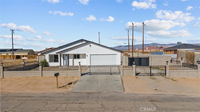 view of front of property featuring a fenced front yard, concrete driveway, an attached garage, and a gate