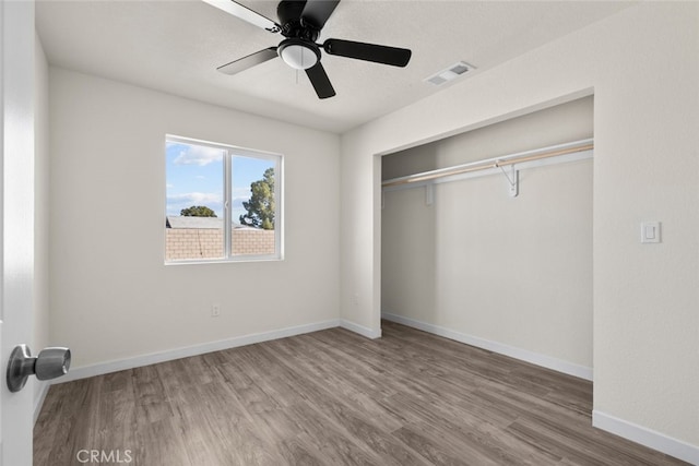 unfurnished bedroom featuring a ceiling fan, wood finished floors, visible vents, baseboards, and a closet