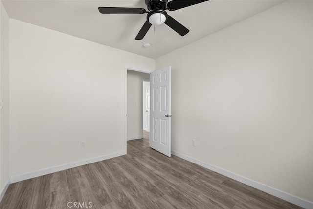 unfurnished room featuring a ceiling fan, baseboards, and wood finished floors