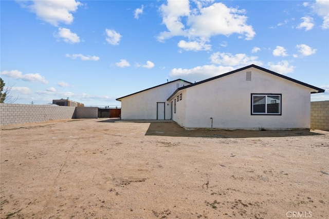 view of side of home featuring fence and stucco siding