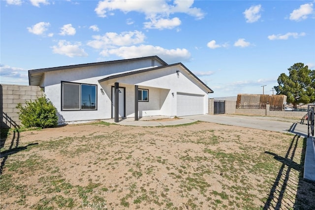 view of front of house with a garage, driveway, stucco siding, and fence