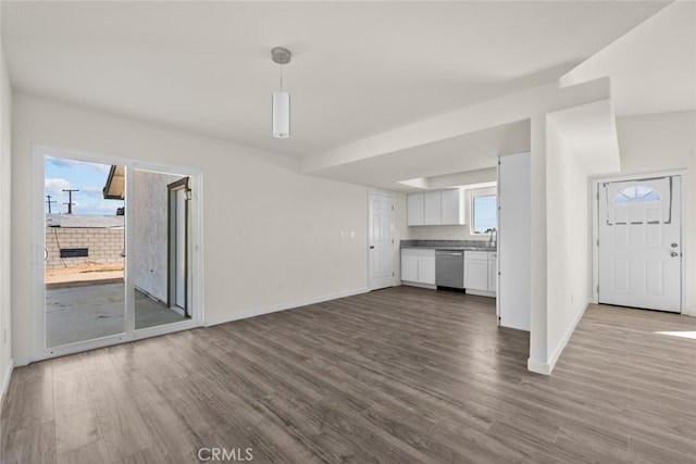 unfurnished living room with dark wood-type flooring, baseboards, and a sink