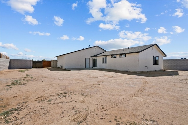 rear view of property featuring stucco siding and a fenced backyard