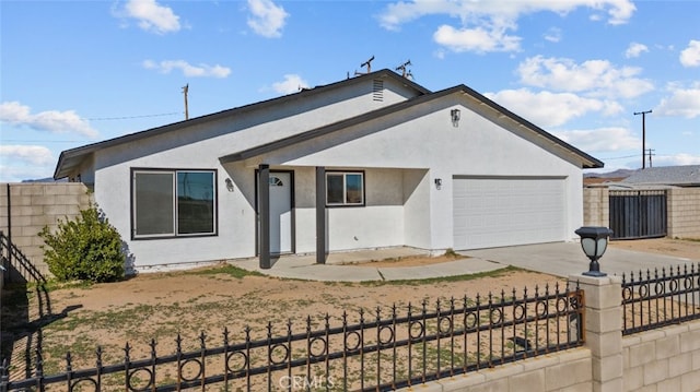 ranch-style house featuring a garage, a fenced front yard, and stucco siding