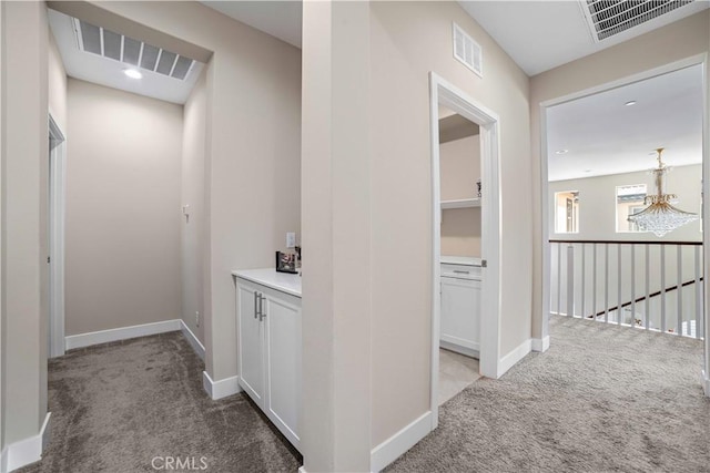hall with baseboards, visible vents, and light colored carpet