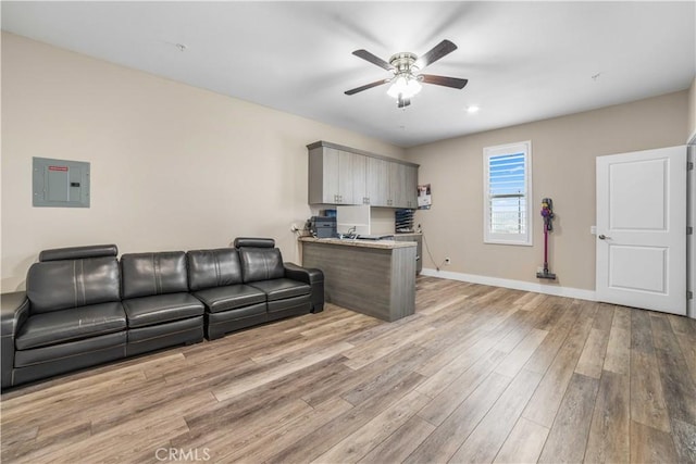 living room featuring light wood finished floors, electric panel, a ceiling fan, and baseboards