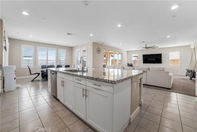 kitchen featuring a kitchen island with sink, stainless steel dishwasher, a sink, light tile patterned flooring, and recessed lighting