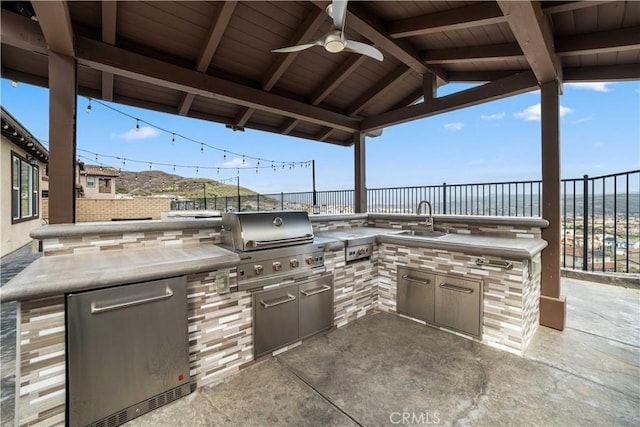 view of patio / terrace featuring a sink, a fenced backyard, an outdoor kitchen, ceiling fan, and grilling area
