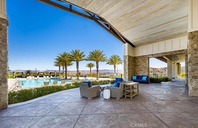view of patio with a community pool, a mountain view, and an outdoor hangout area