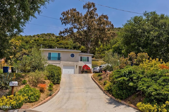 view of front of property with concrete driveway, a balcony, an attached garage, and stucco siding