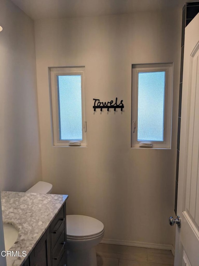 bathroom featuring toilet, vanity, and baseboards