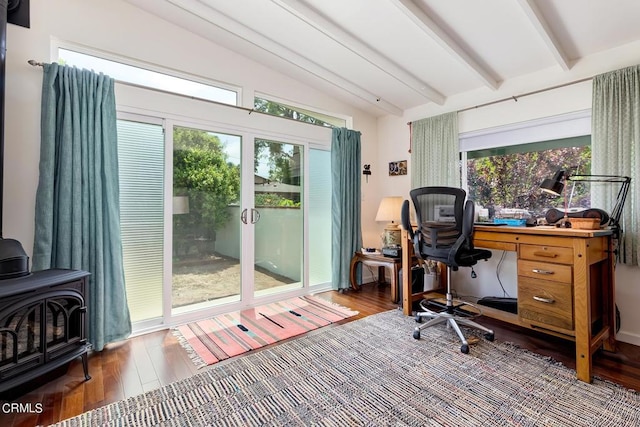 home office with vaulted ceiling with beams, a wood stove, and wood finished floors