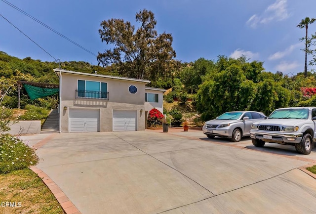 view of front facade featuring a balcony, stucco siding, driveway, and a garage