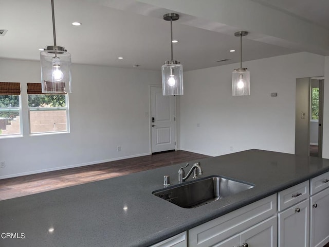 kitchen featuring a sink, decorative light fixtures, dark countertops, and white cabinets