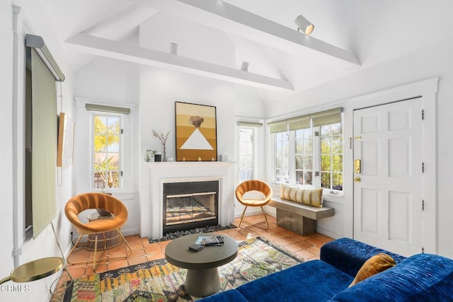 tiled living room featuring a fireplace with flush hearth, a wealth of natural light, and vaulted ceiling with beams