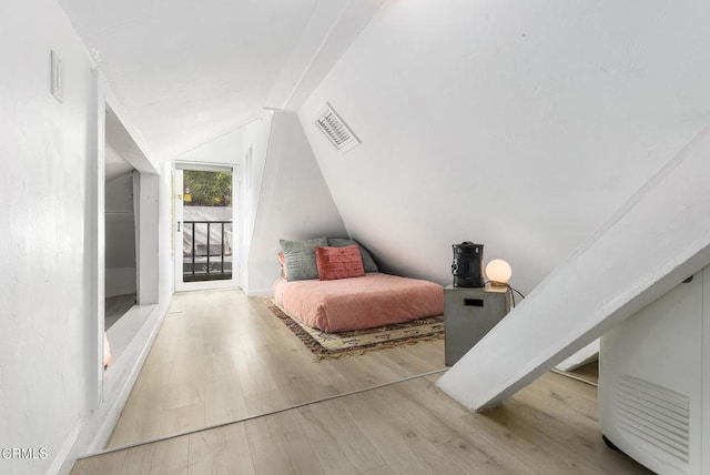 bedroom with visible vents, vaulted ceiling, wood finished floors, and access to exterior