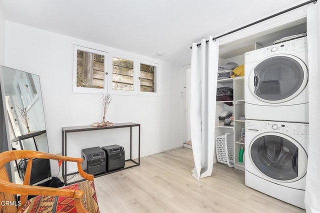 laundry room featuring baseboards, laundry area, stacked washing maching and dryer, and wood finished floors