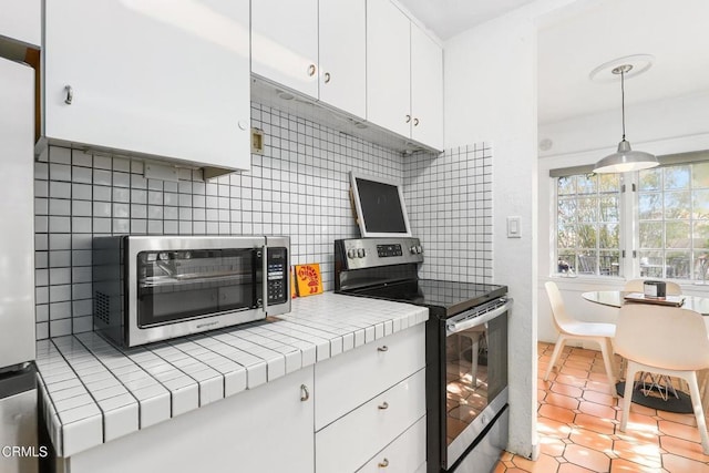 kitchen featuring stainless steel electric range, tile counters, white cabinetry, decorative backsplash, and a toaster
