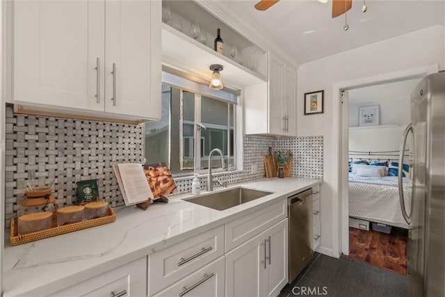 kitchen with white cabinets, light stone counters, a sink, decorative backsplash, and appliances with stainless steel finishes