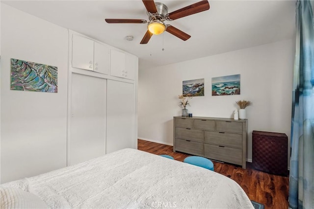 bedroom featuring a ceiling fan, baseboards, dark wood-style flooring, and a closet