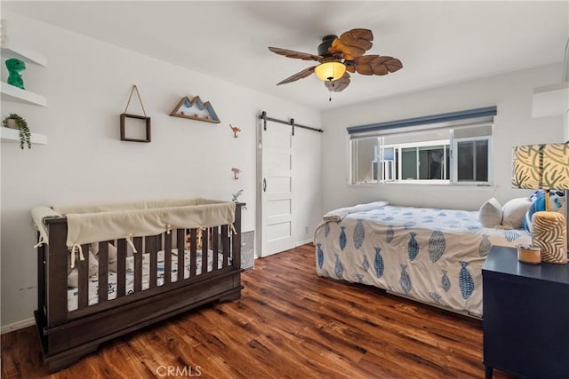 bedroom with a ceiling fan, wood finished floors, and a barn door