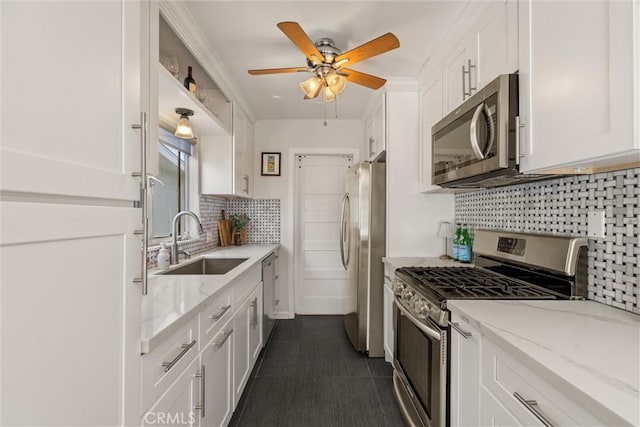 kitchen with a sink, decorative backsplash, ceiling fan, stainless steel appliances, and white cabinets