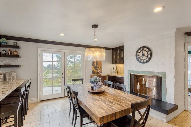 dining room with recessed lighting, an inviting chandelier, stone tile flooring, a fireplace with raised hearth, and baseboards