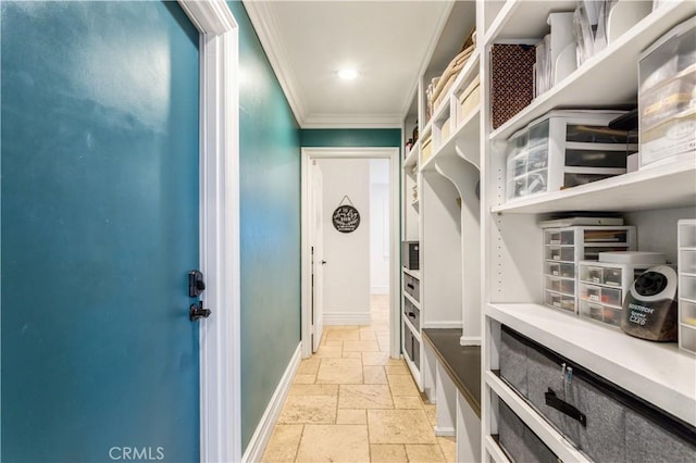 mudroom with stone tile floors, ornamental molding, and baseboards