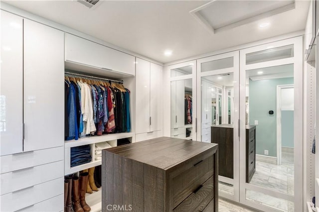 walk in closet featuring attic access, visible vents, and marble finish floor