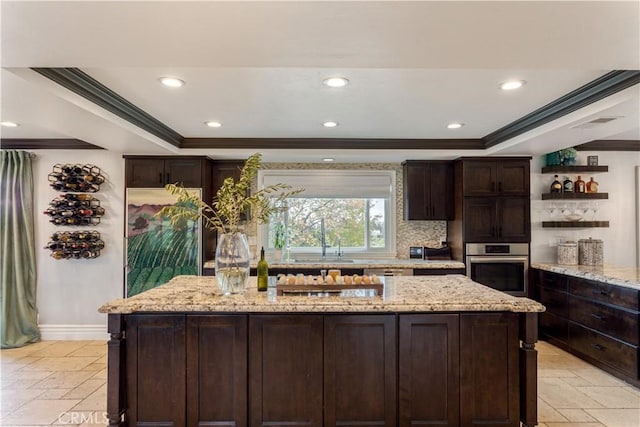 kitchen featuring ornamental molding, a tray ceiling, stone tile floors, and oven