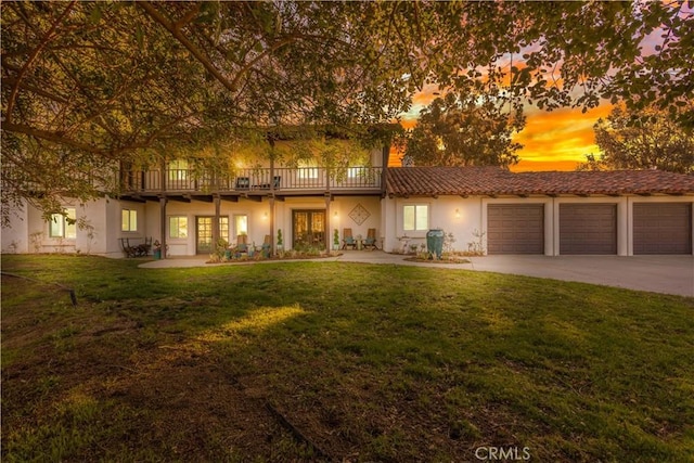 view of front of house featuring french doors, stucco siding, driveway, and a lawn